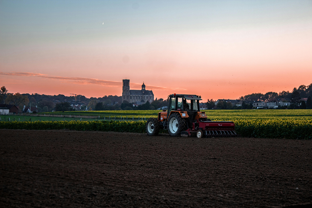Tractor in rural field at sunset